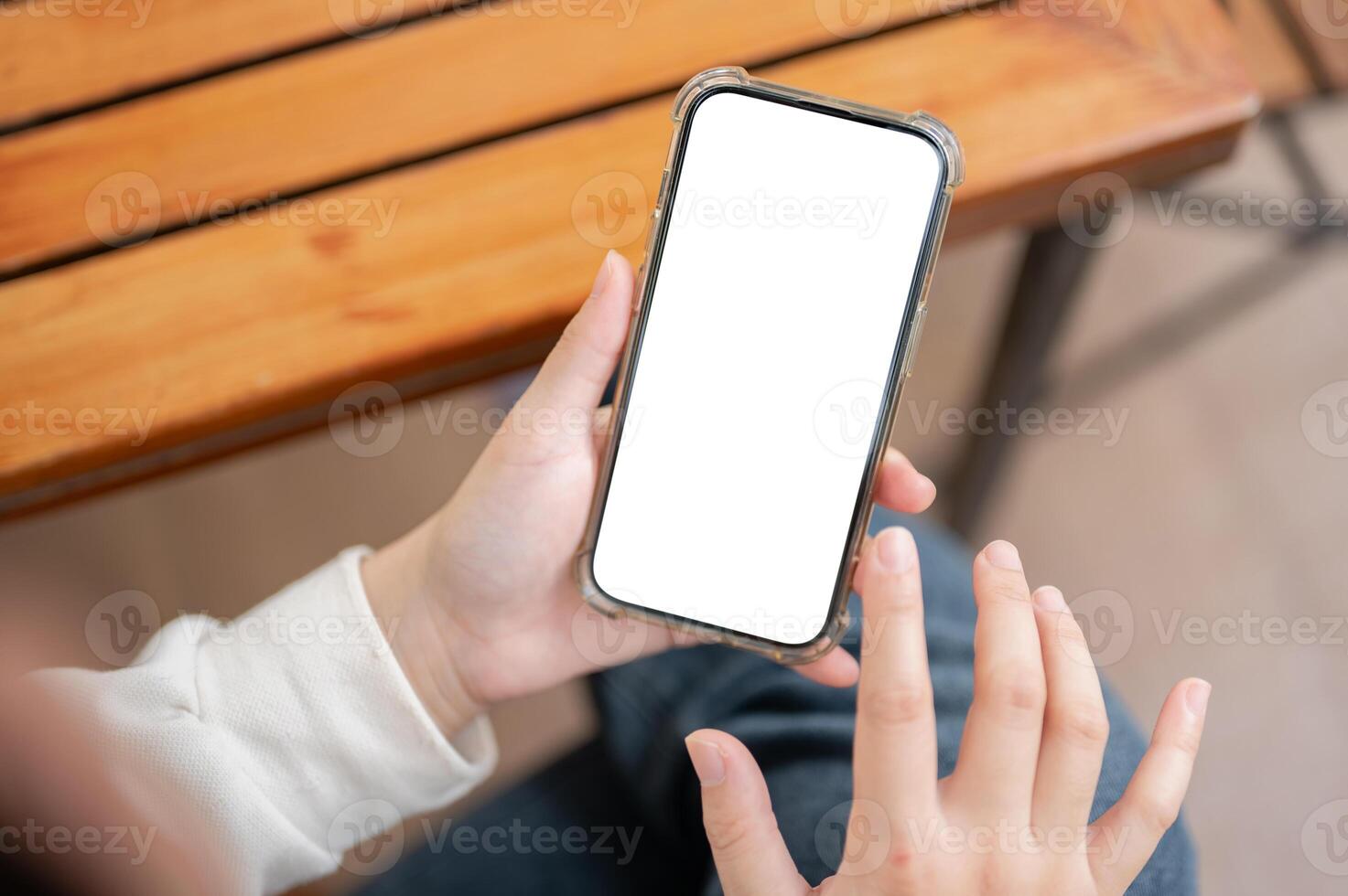A close-up image of a woman in casual clothes using her smartphone at a table indoors. photo