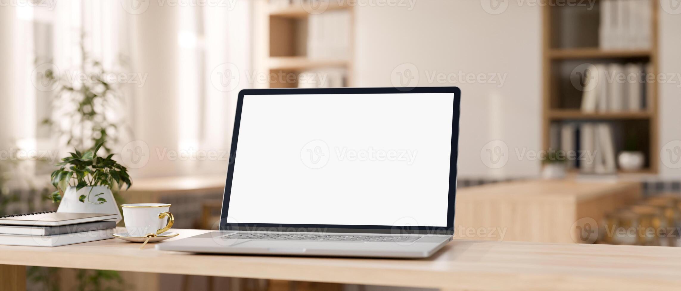 A laptop computer mockup on a wooden tabletop in a contemporary minimalist cafe co-working space. photo