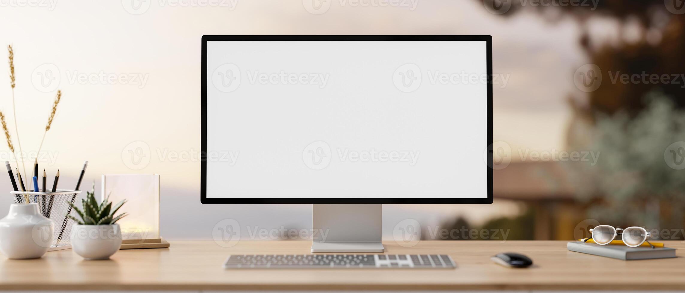A PC computer mockup and accessories on a wooden desk with a blurred background of an outdoors. photo