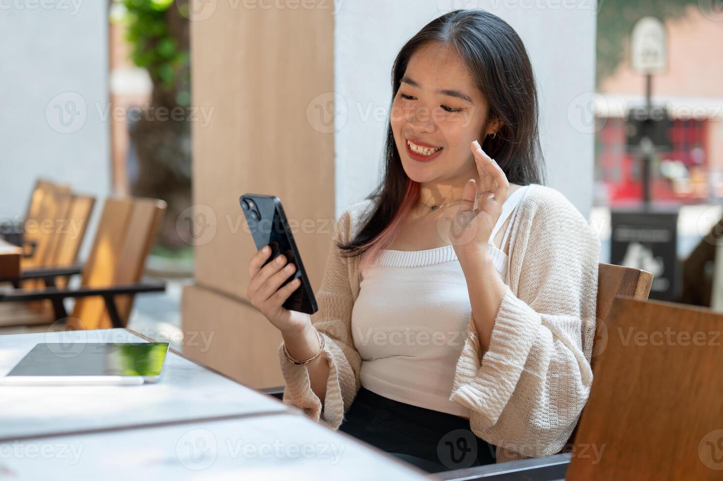 A cheerful Asian woman enjoys talking on a call while chilling at a restaurant in the city. photo
