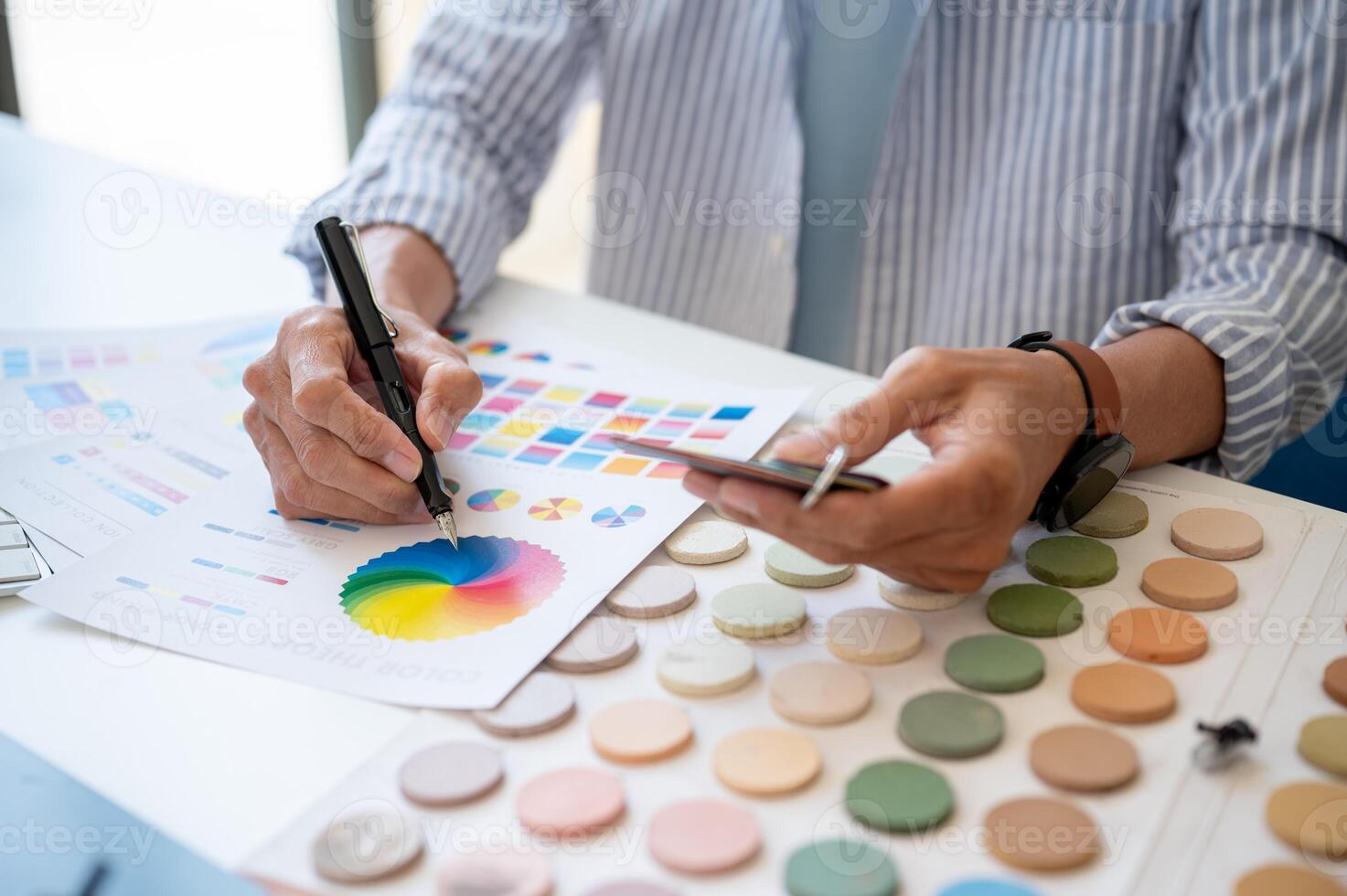 A professional male interior designer working at his desk in the studio, checking samples. photo