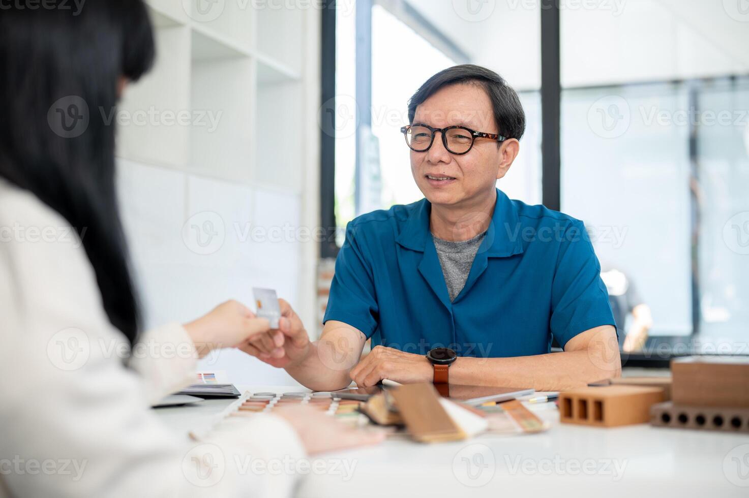 A male interior designer or contractor receives a credit card from a client during the meeting. photo