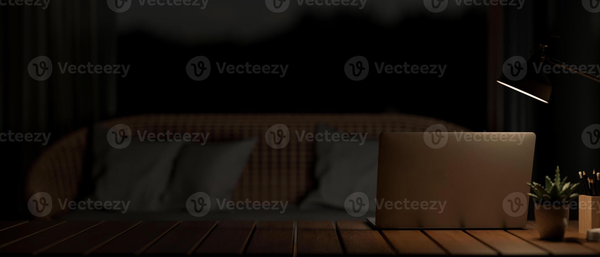 A laptop under a dim light from a lamp on a coffee table in a modern dark living room at night. photo