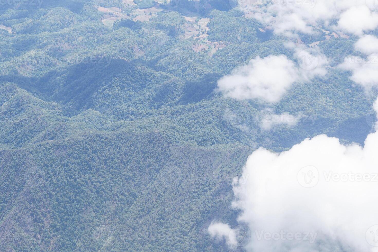 Aerial view of lands and clouds seen through airplane window photo