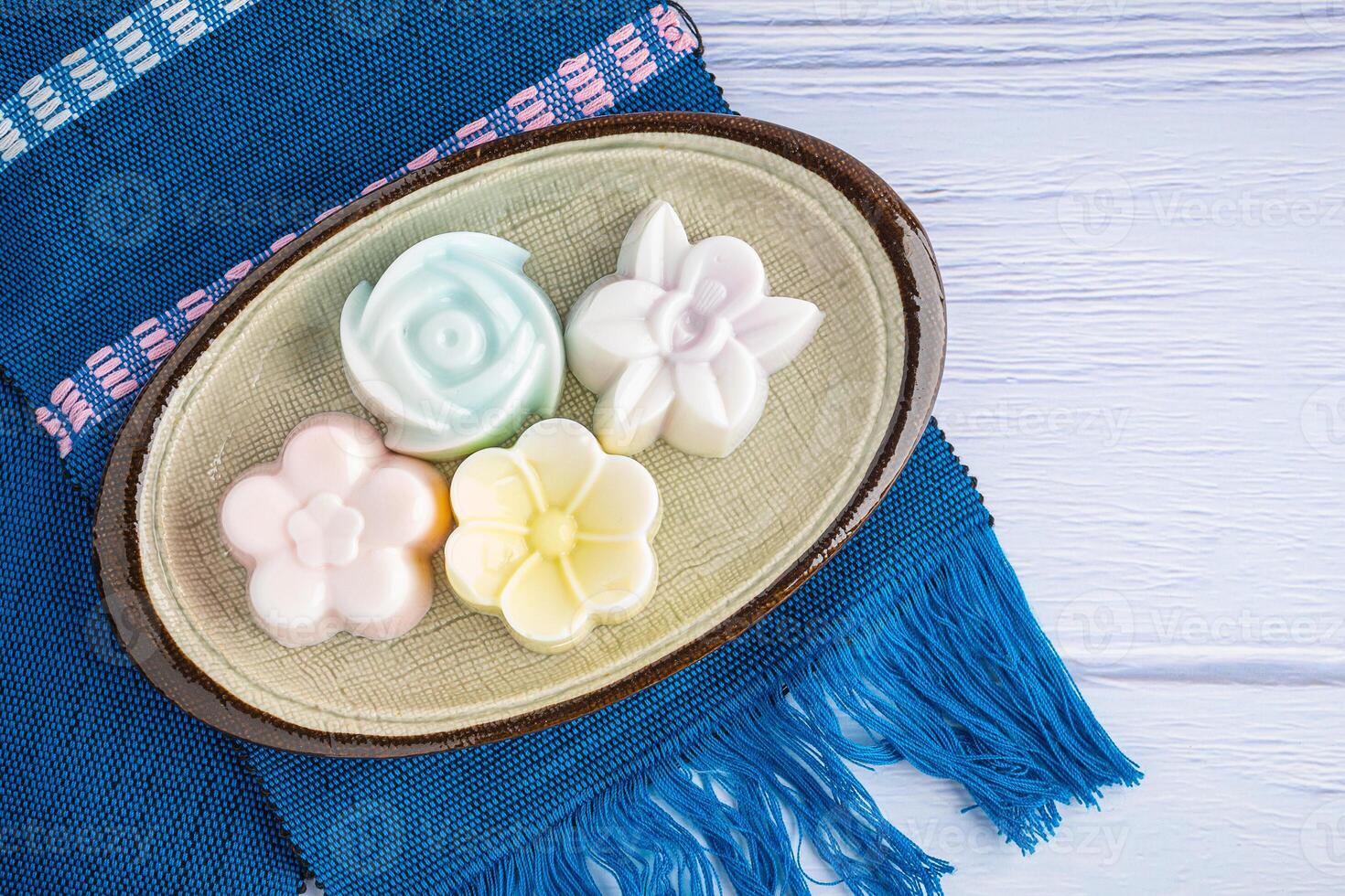 Top view of colorful coconut milk jelly on a plate on a blue cloth. Space for text. Concept of Thai dessert photo