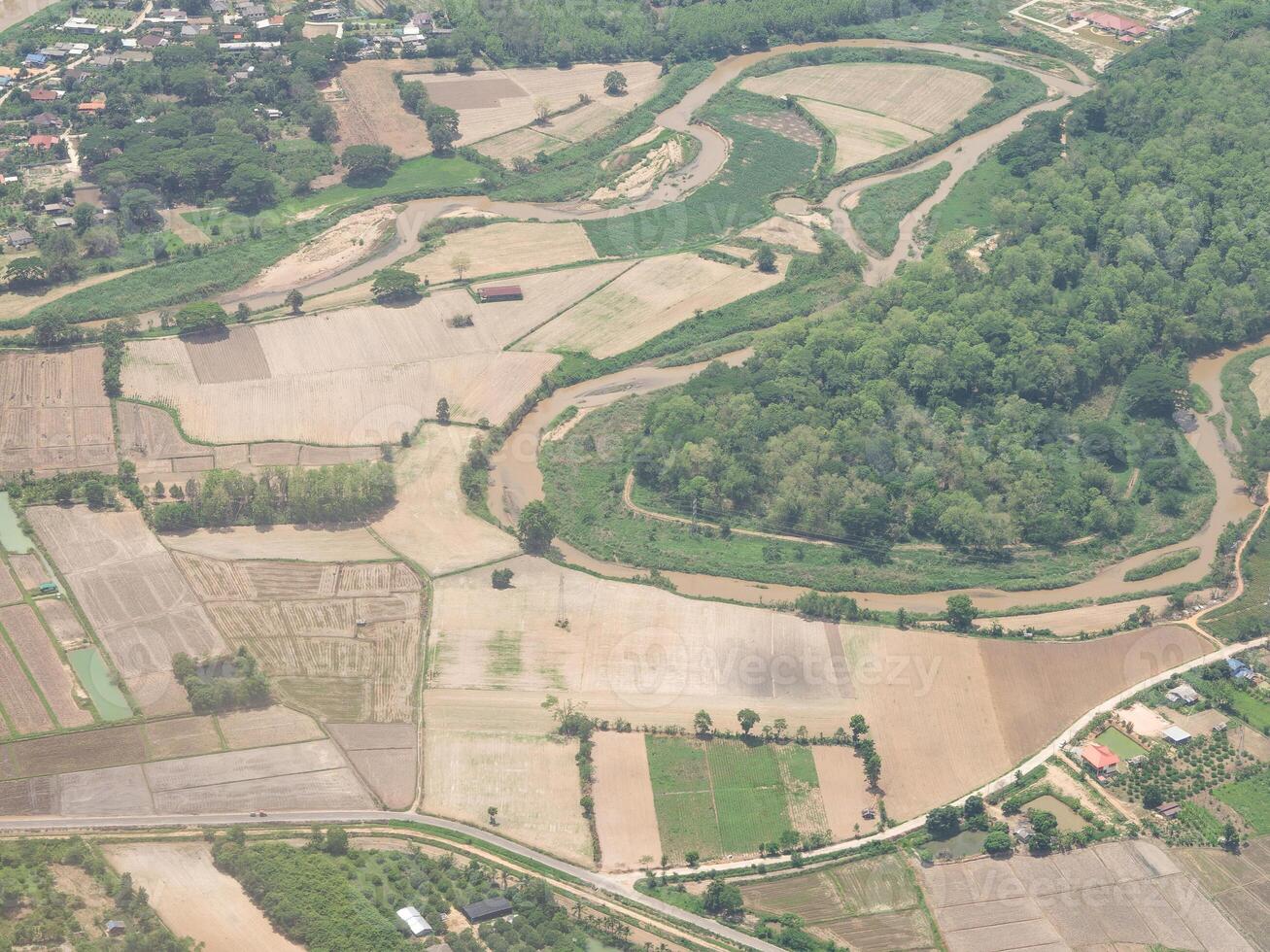 Aerial view of agricultural fields, river, mountains, and land have seen through the airplane window photo