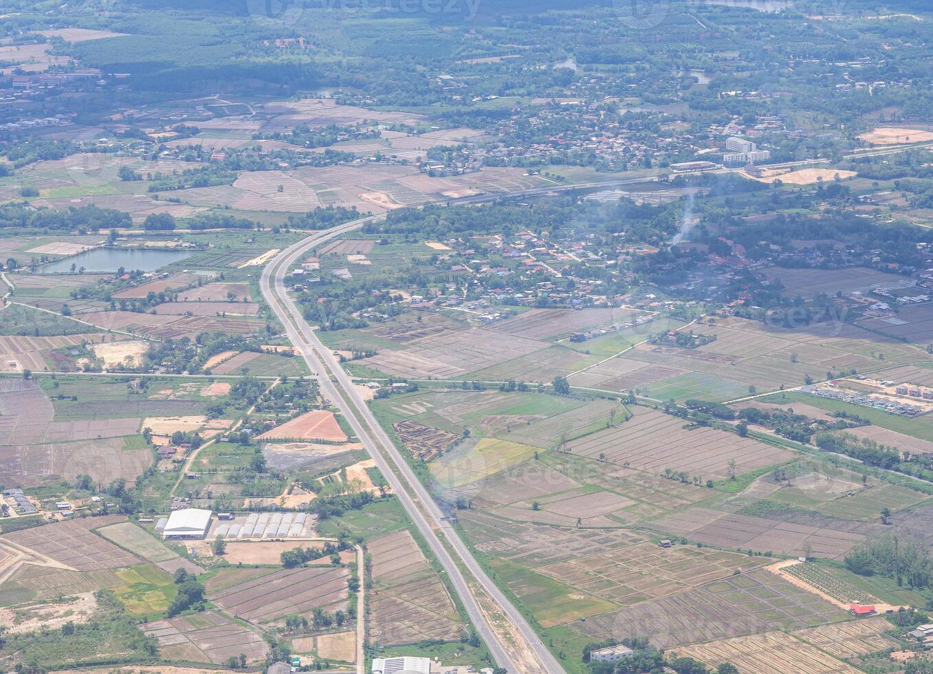 Aerial view of agricultural field, river, road, and townscape is seen through the airplane window photo