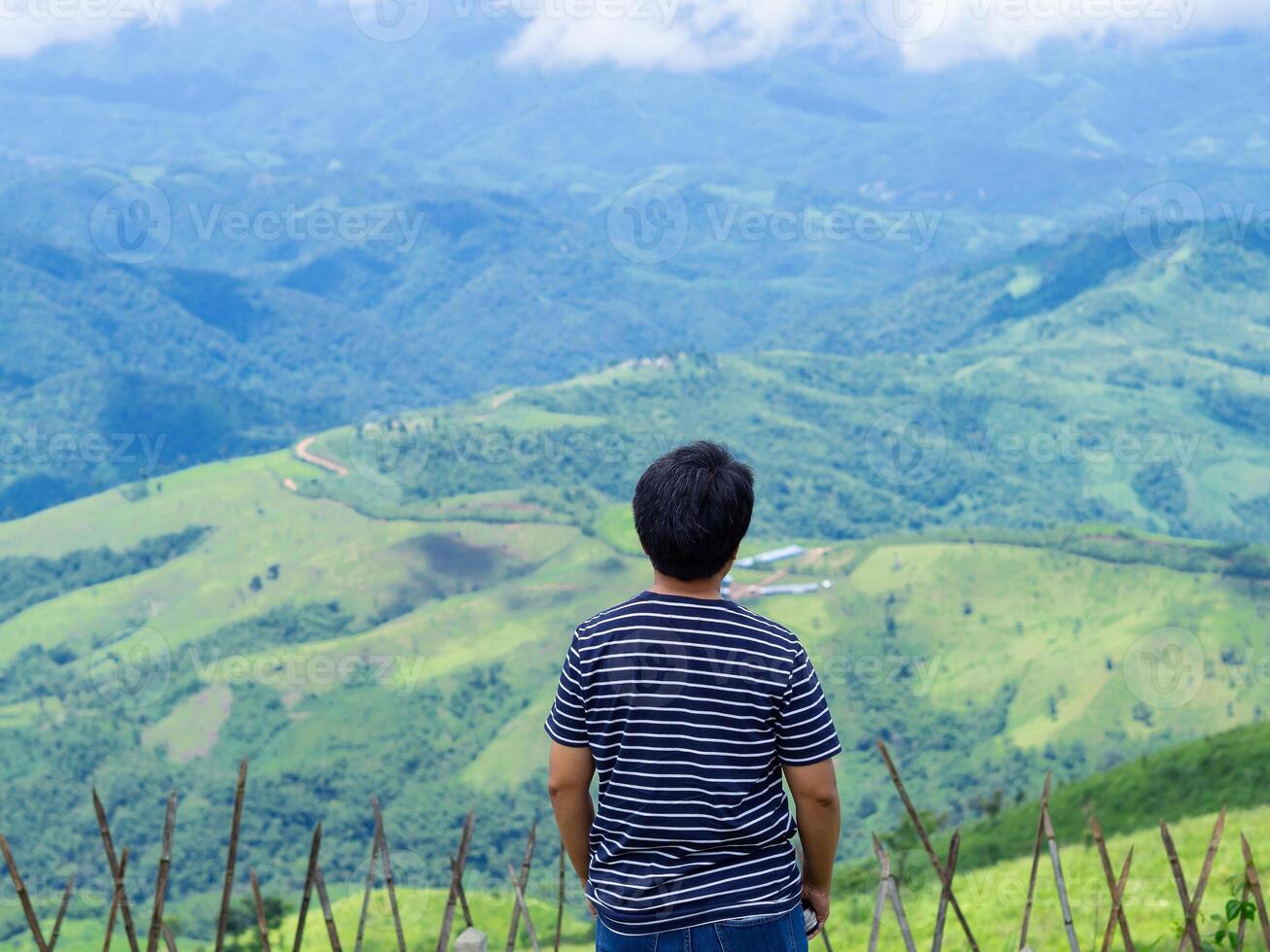 Back view of traveler looking at the amazing scenic view of mountains with clouds background. Travel concept photo