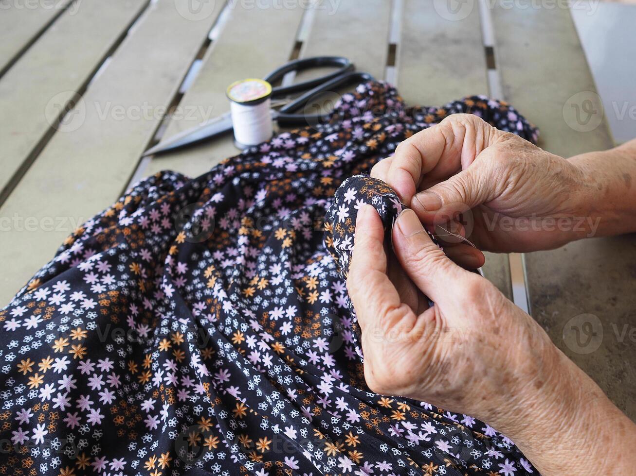 Close-up of hands senior woman's trying to thread a needle for sewing cloth. Space for text. Concept of aged people and relaxation photo