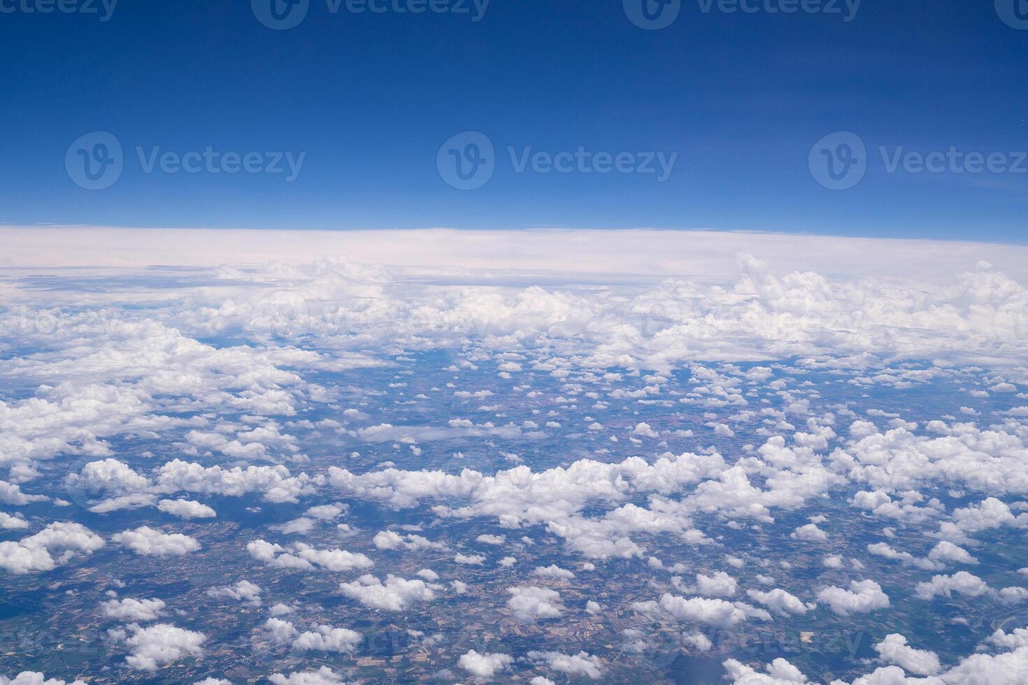 Aerial view of agricultural field, river, and clouds are seen through the airplane window photo