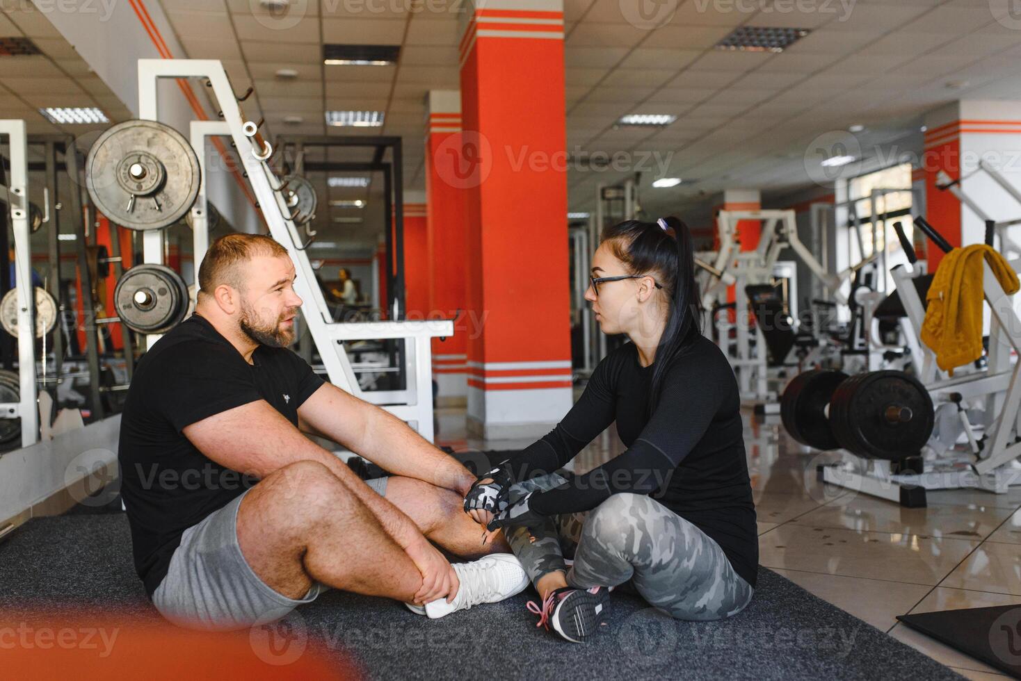 Fitness, sports, exercises and weightlifting. Concept - a young woman and a young man with dumbbells sweeping muscles in the gym photo