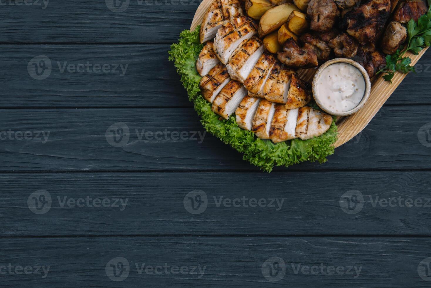 Most meat dish - beef kebabs, sausages, grilled mushrooms, potatoes, tomatoes and sauce. The best choice for a beer. Close-up on a wooden background. photo