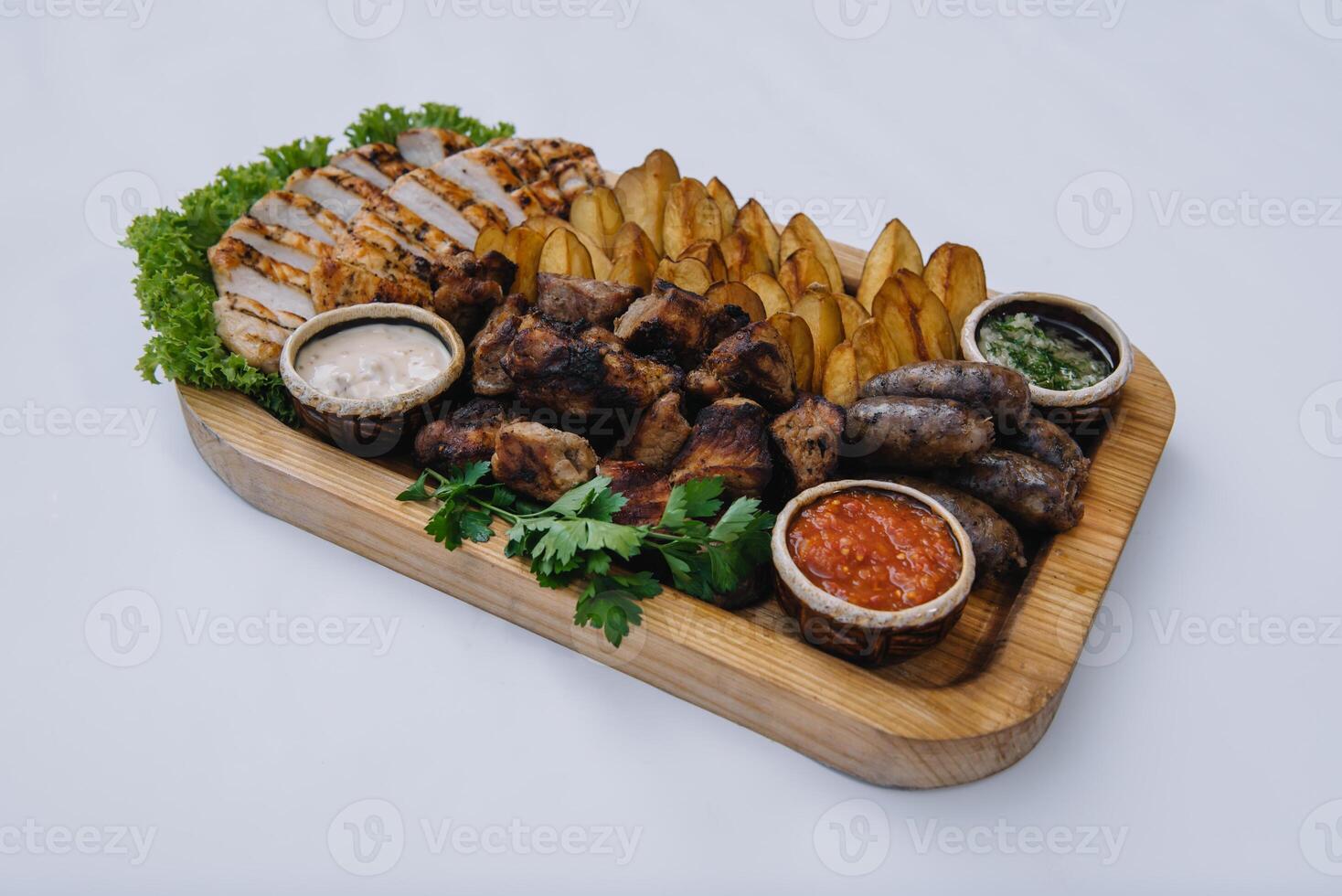 Most meat dish - beef kebabs, sausages, grilled mushrooms, potatoes, tomatoes and sauce. The best choice for a beer. Close-up on a white background photo
