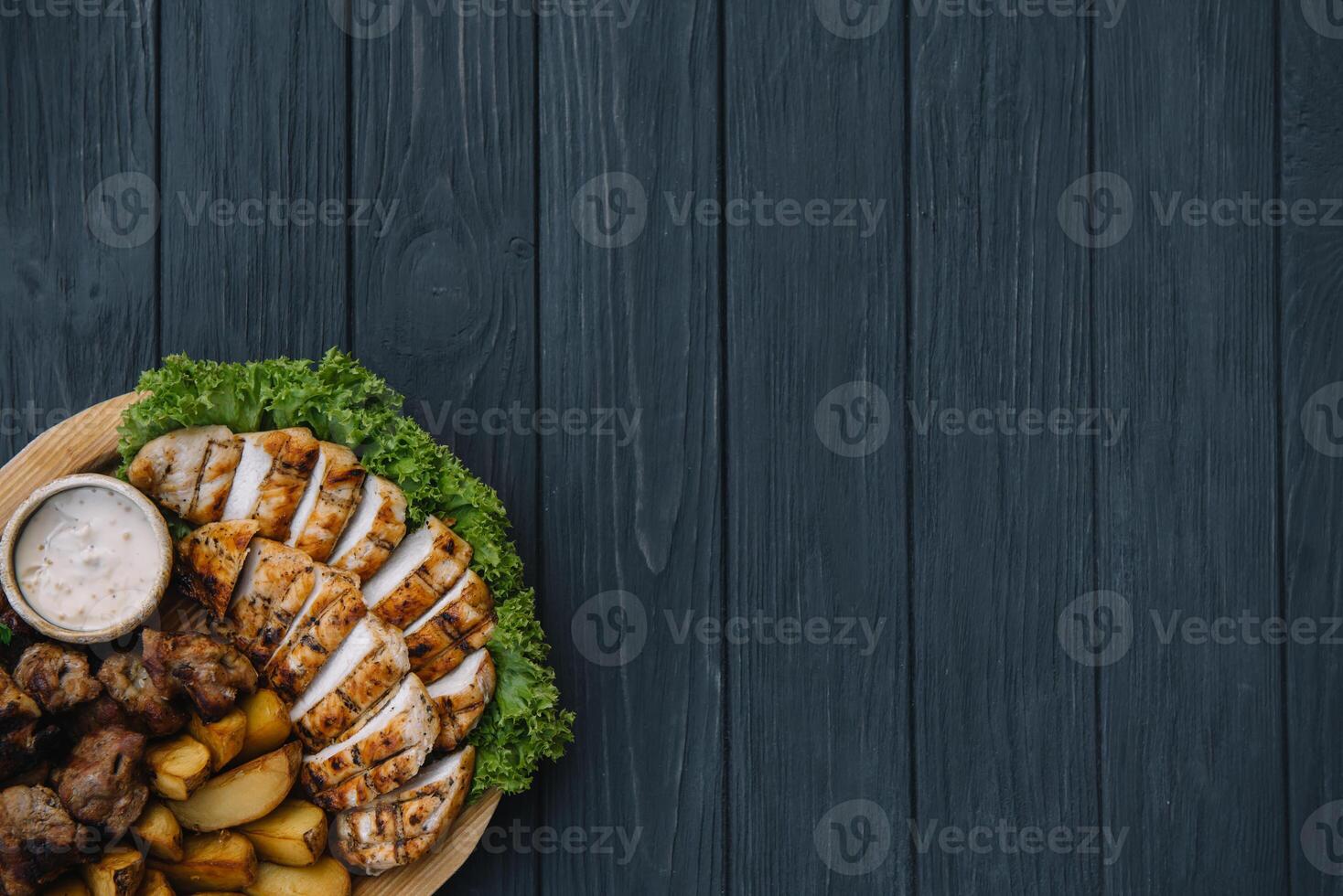 Most meat dish - beef kebabs, sausages, grilled mushrooms, potatoes, tomatoes and sauce. The best choice for a beer. Close-up on a wooden background. photo