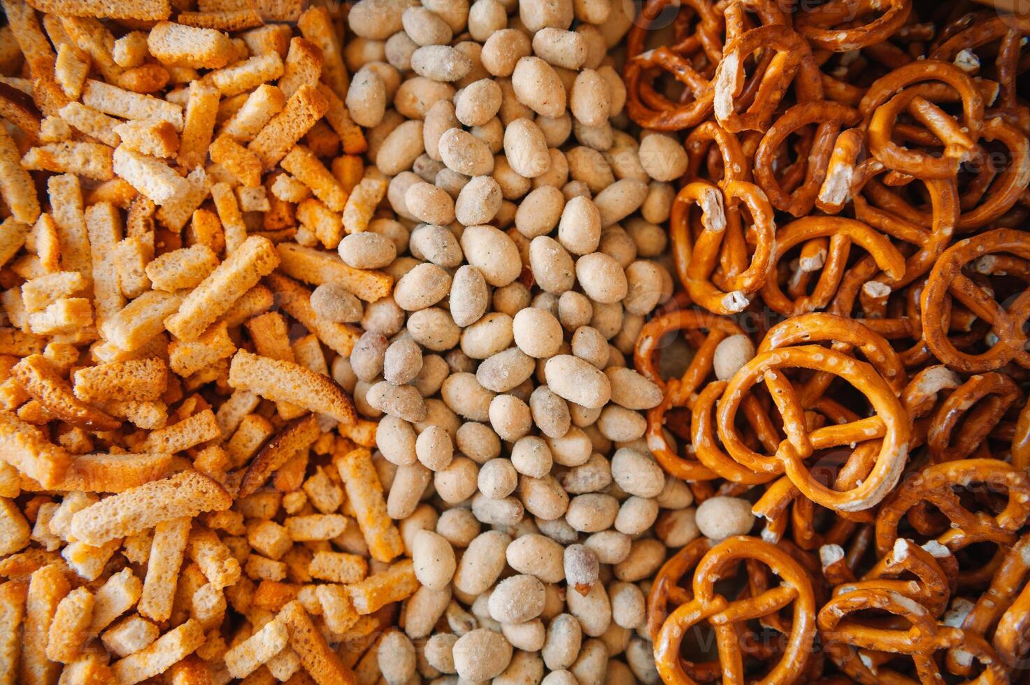 Mix of snacks pretzels , crackers , chips , nuts and nachos. Lager beer and snacks on stone table. Nuts, chips, pretzel. Top view with copy space. photo