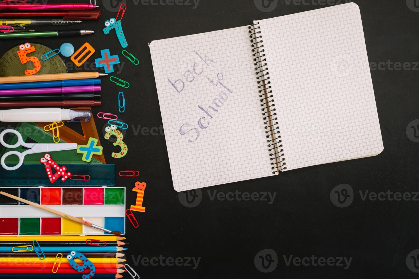 Back to school concept. School and office supplies on blackboard background photo