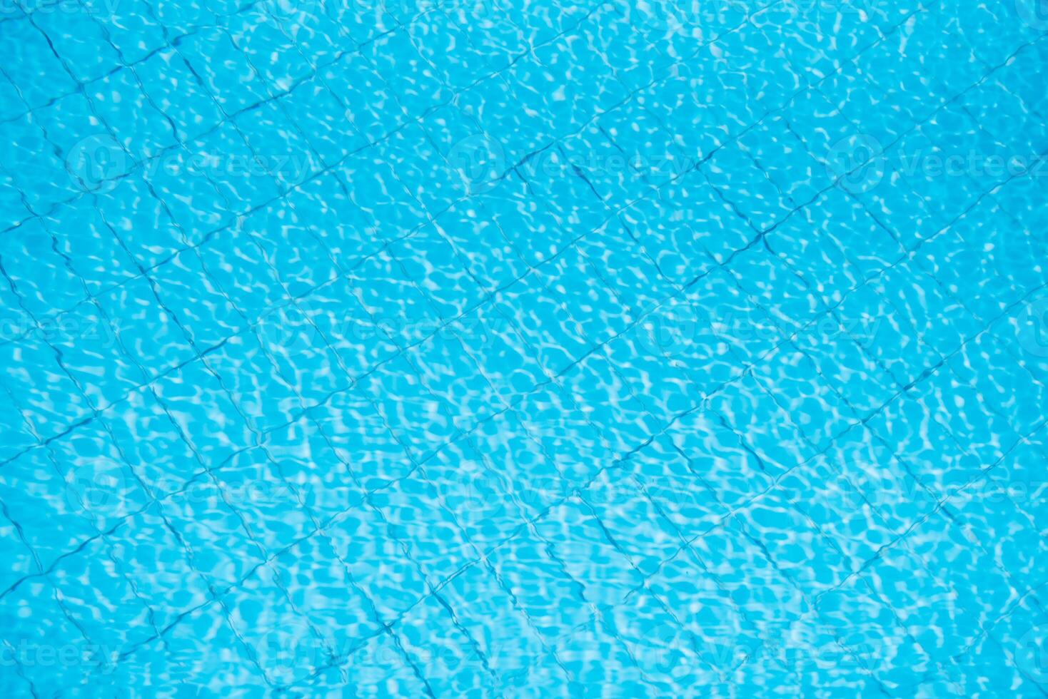 Water ripples on blue tiled swimming pool background. View from above. photo
