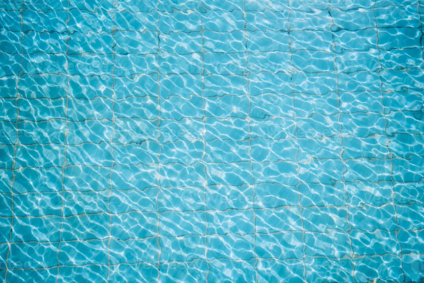 Water ripples on blue tiled swimming pool background. View from above. photo