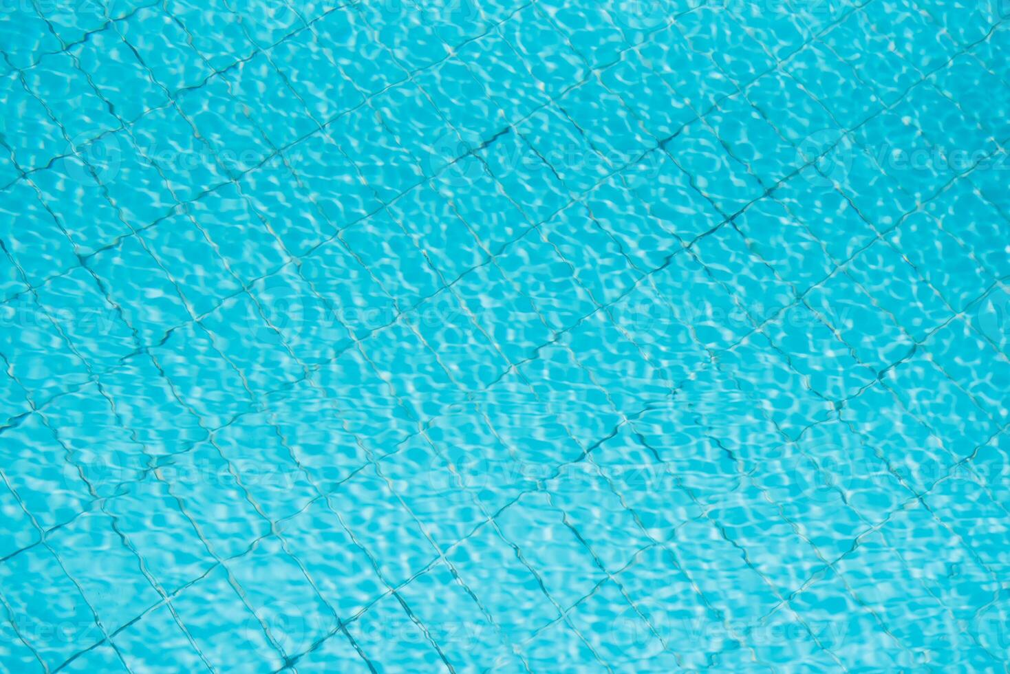 Water ripples on blue tiled swimming pool background. View from above. photo