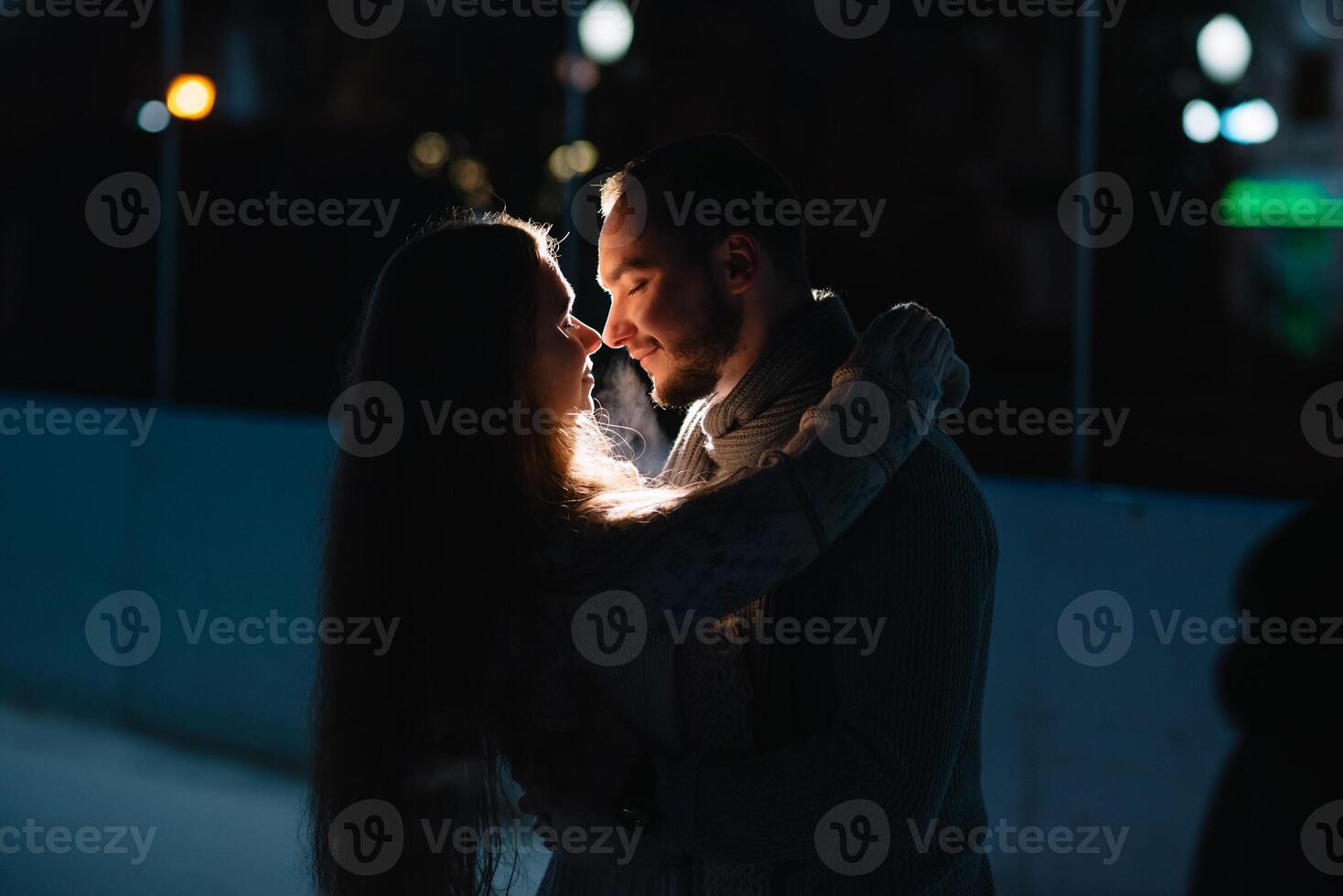 Happy attractive couple in a christmas market at night. Beautiful bokeh lights background. photo