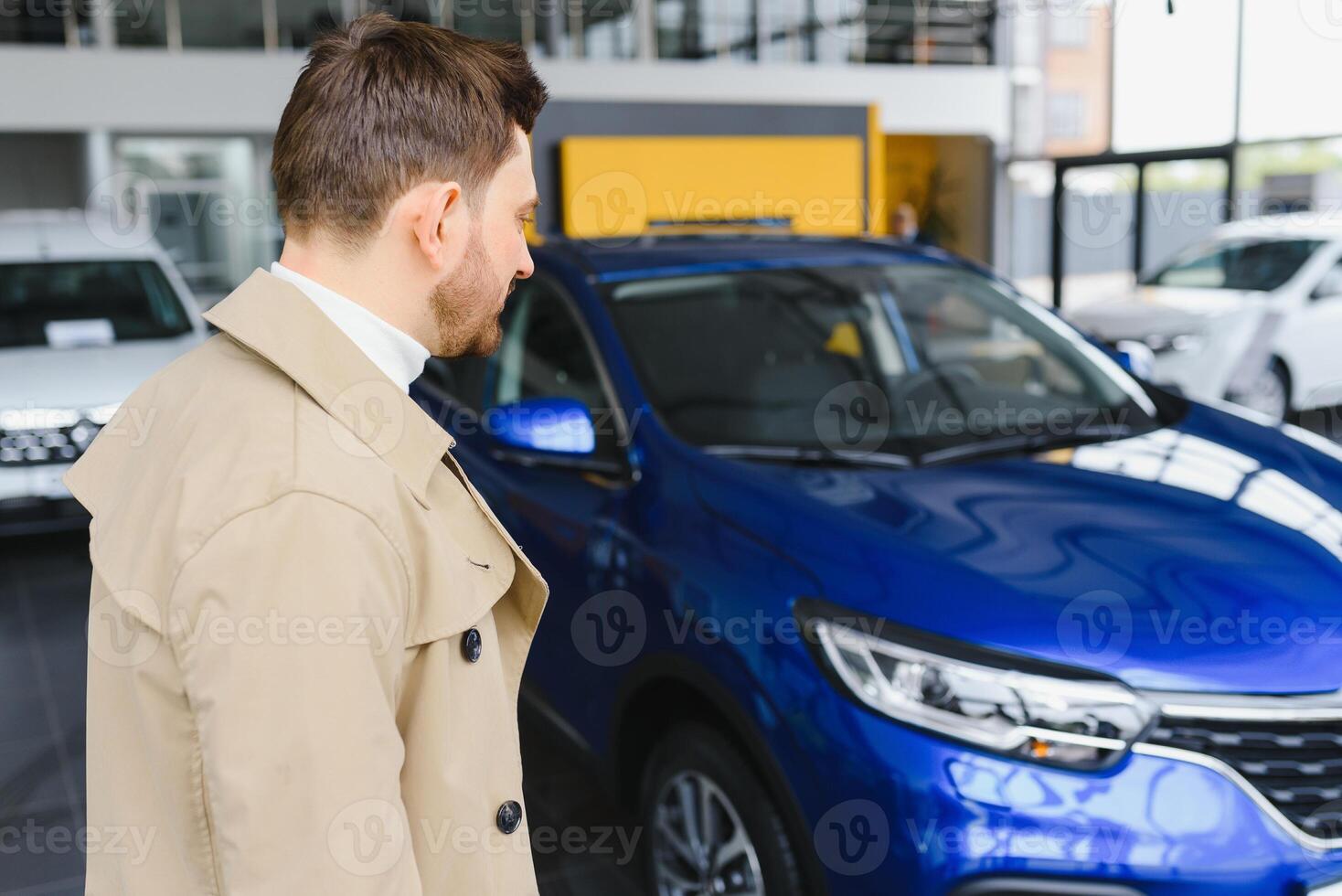 Making his choice. Horizontal portrait of a young man in a suit looking at the car and thinking if he should buy it photo