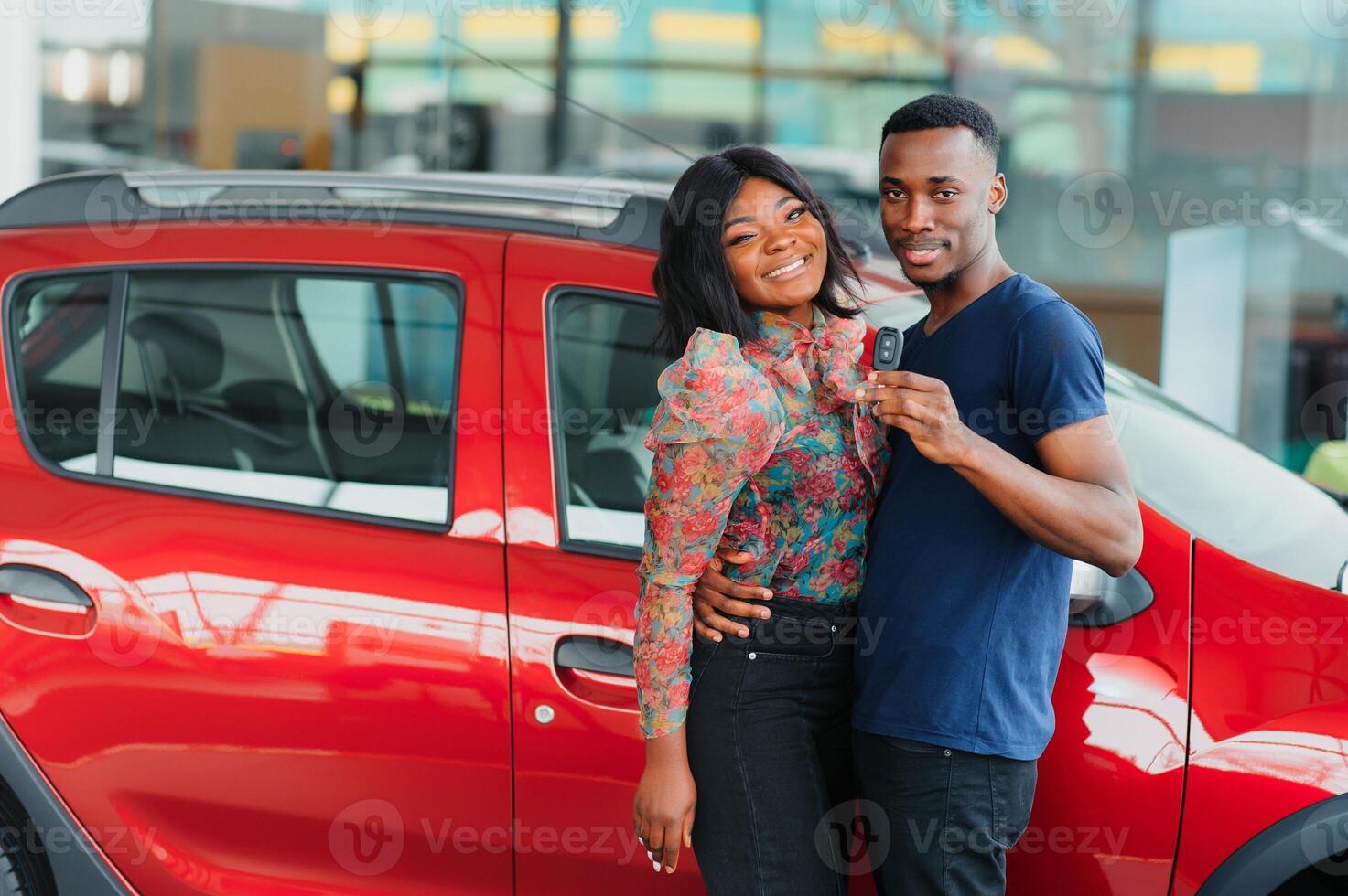 Smiling African American couple hugging and smiling at camera at new car showroom photo
