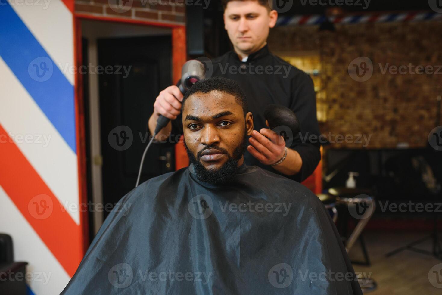 Closeup of process of trimming of hair in barber shop. Qualified barber keeping clipper in hands and correcting shape of hair to male client sitting on chair. Concept of haircut and shaving. photo
