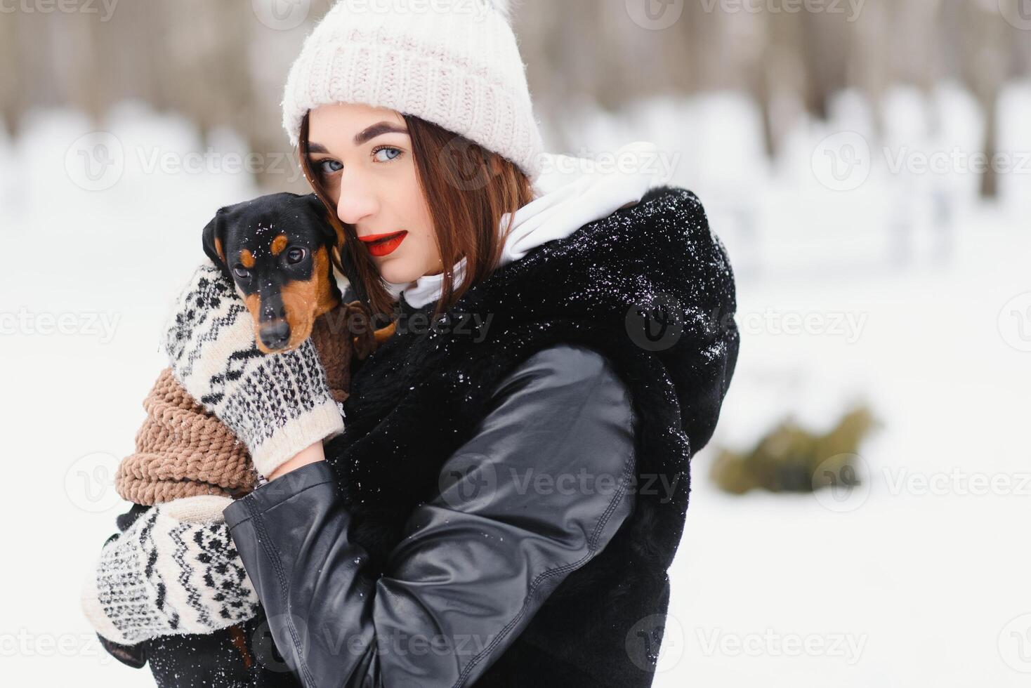 Young stylish woman with a dog having fun in a winter forest. photo