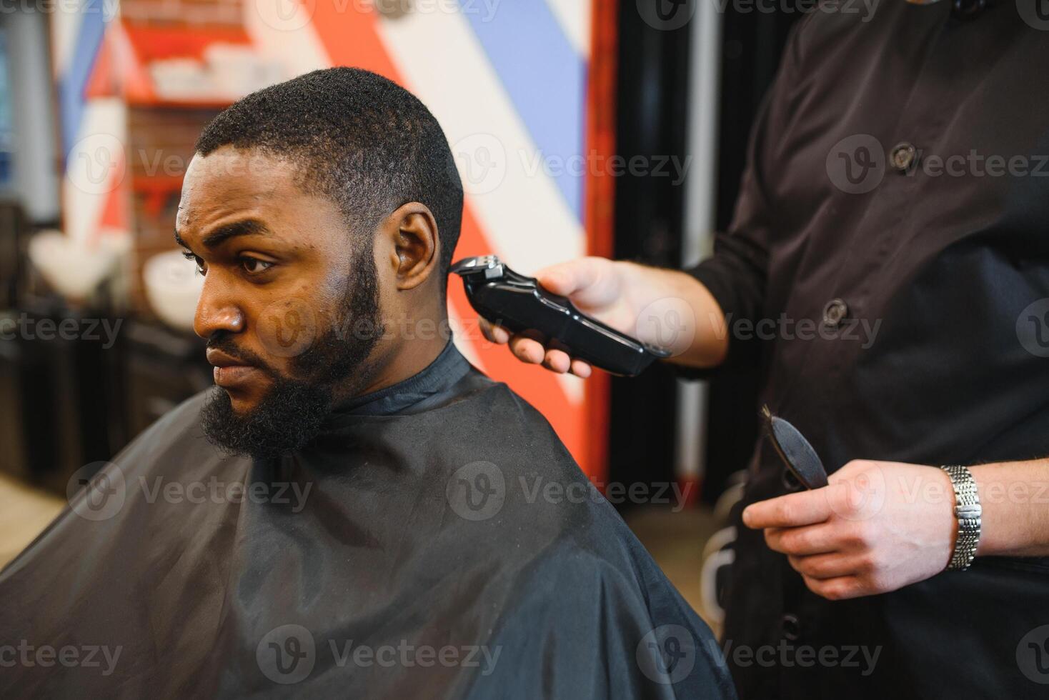Closeup of process of trimming of hair in barber shop. Qualified barber keeping clipper in hands and correcting shape of hair to male client sitting on chair. Concept of haircut and shaving. photo
