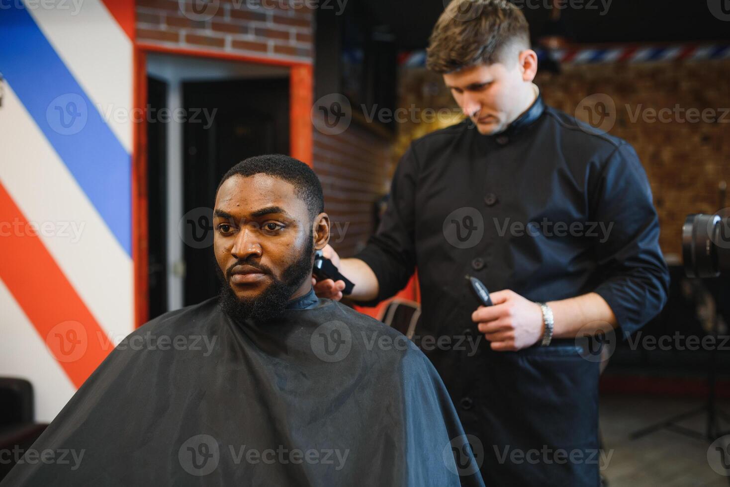 Closeup of process of trimming of hair in barber shop. Qualified barber keeping clipper in hands and correcting shape of hair to male client sitting on chair. Concept of haircut and shaving. photo