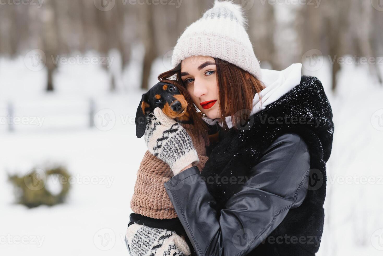 Young stylish woman with a dog having fun in a winter forest. photo