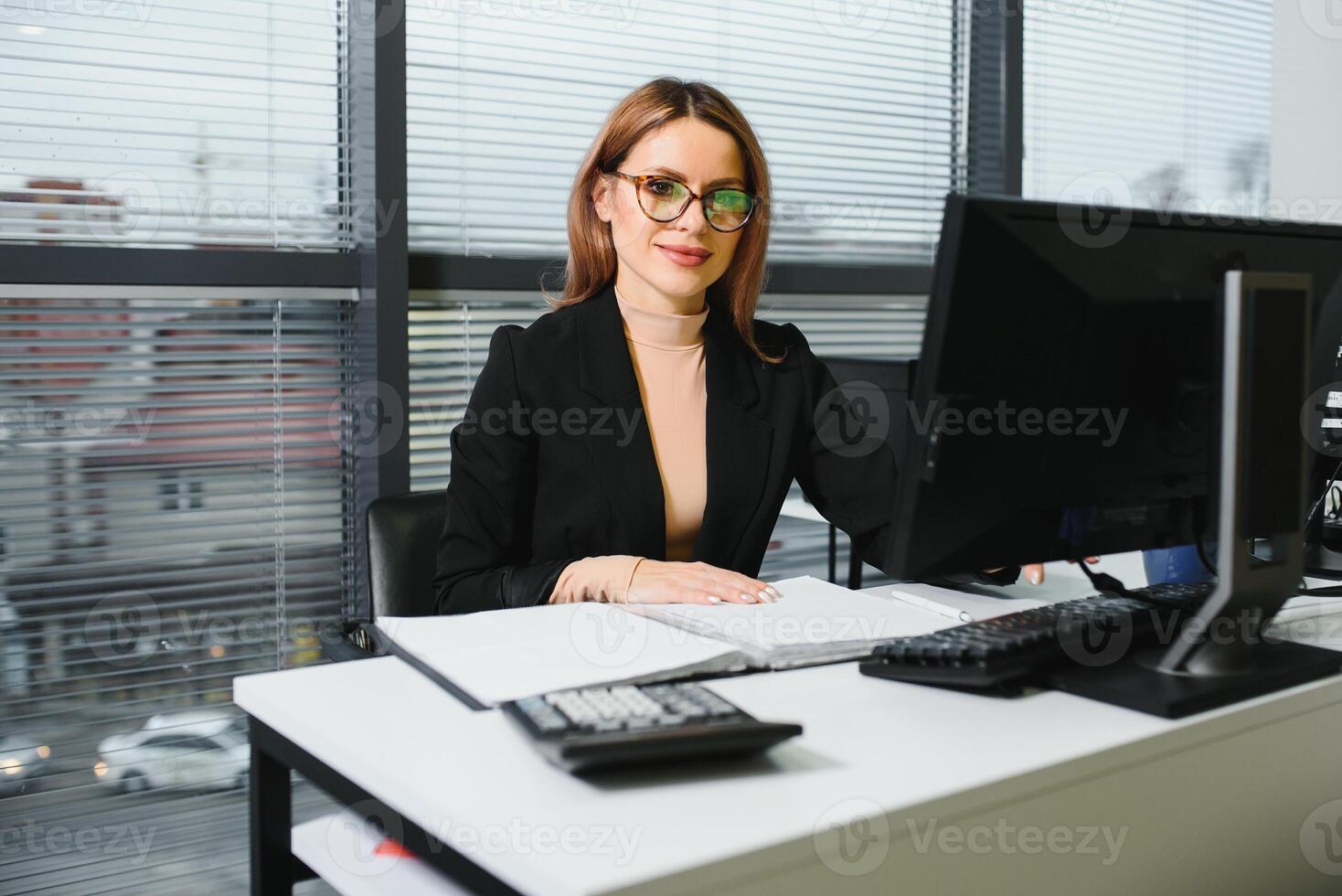 Young businesswoman sitting at workplace and reading paper in office photo