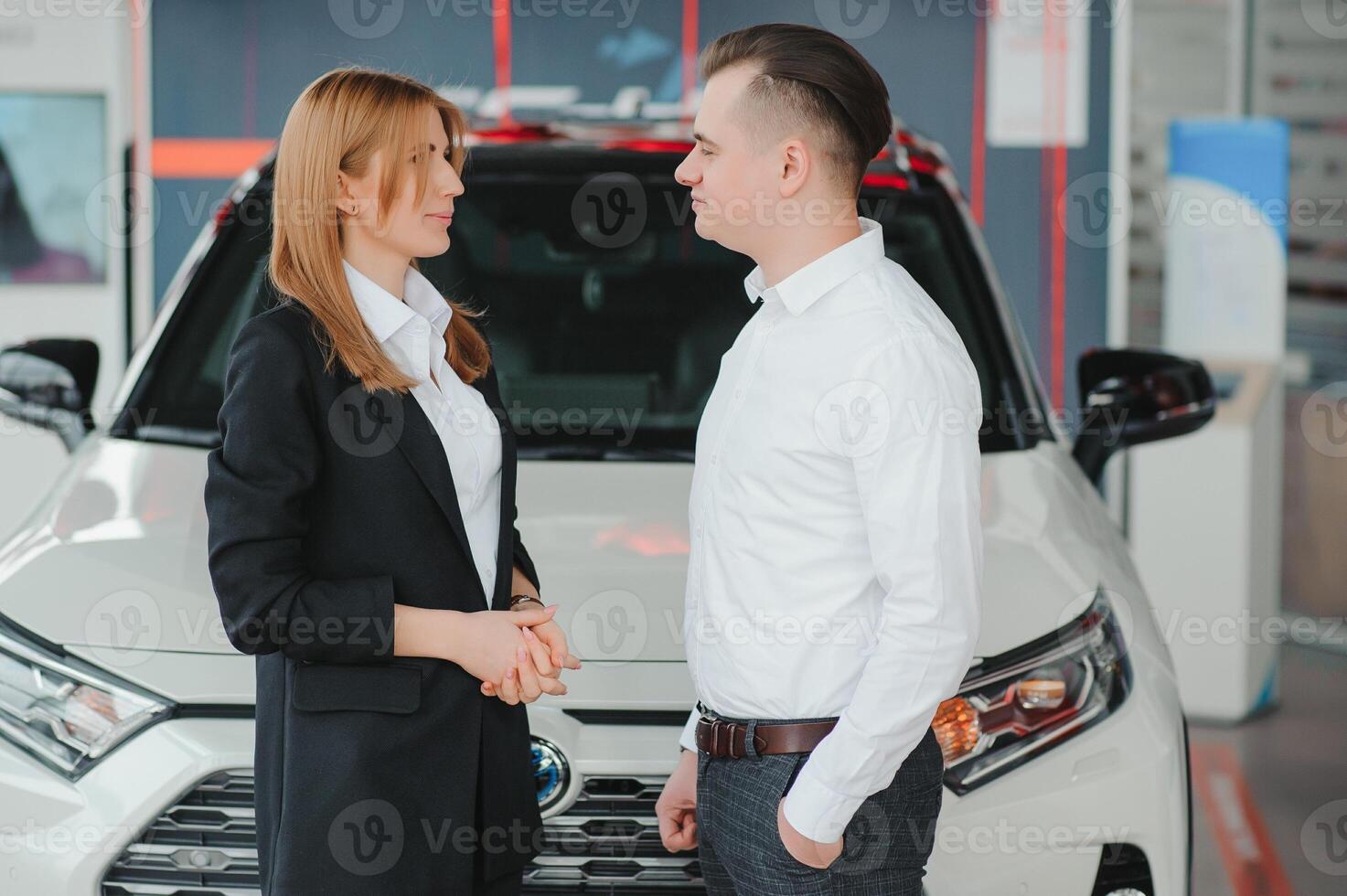Young couple byuing a car in a car showroom. photo