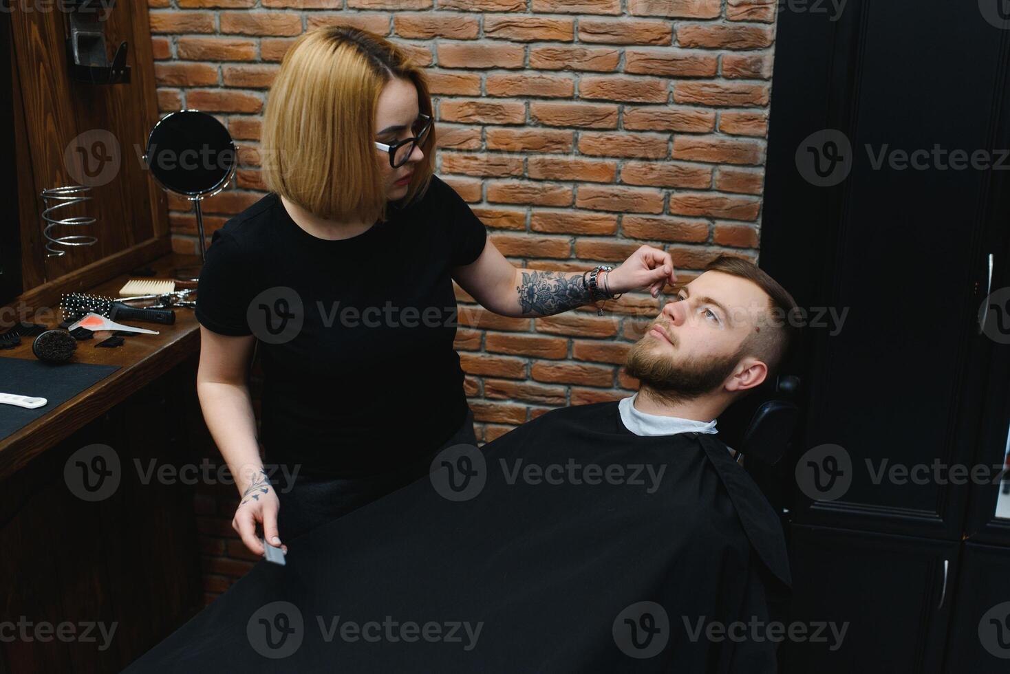 Client during beard shaving in barber shop photo