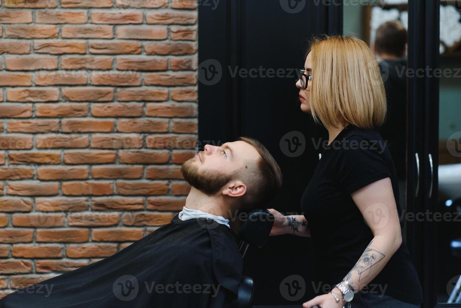 Client during beard shaving in barber shop photo