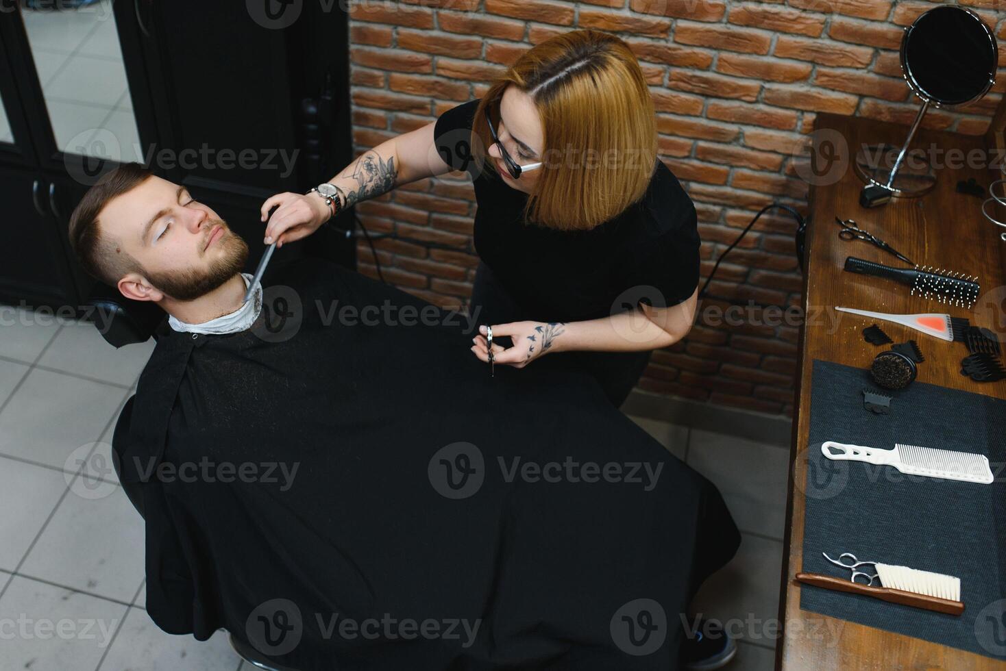Client during beard shaving in barber shop photo