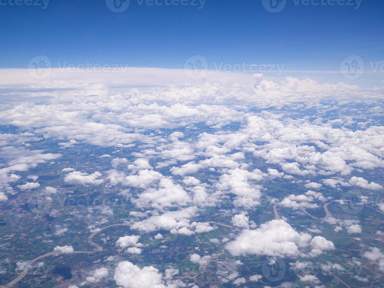 Aerial view of agricultural field, river and clouds seen through airplane window photo