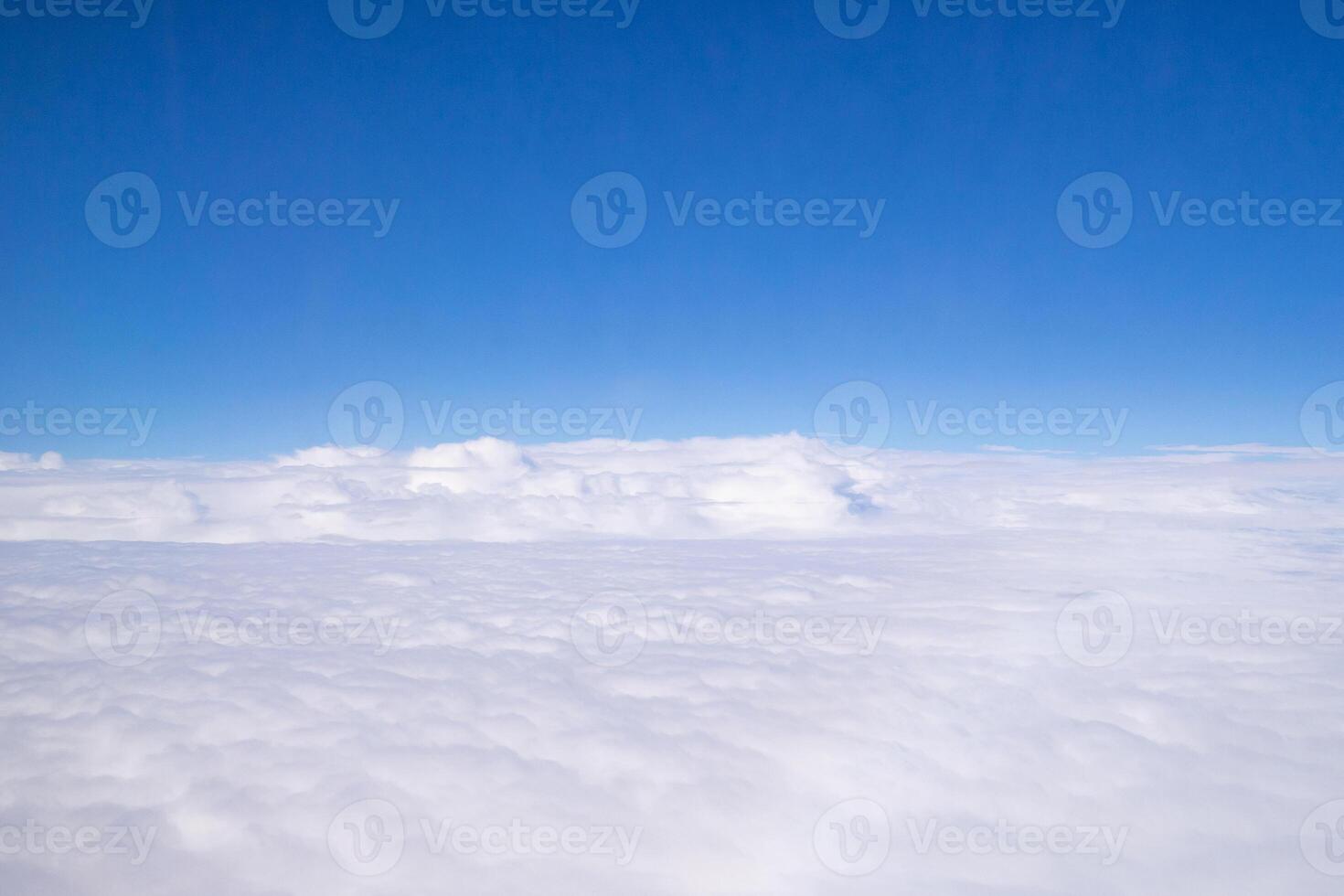Aerial view of sky seen through the airplane window. Bright blue sky and white clouds with skyline background. Space for text photo