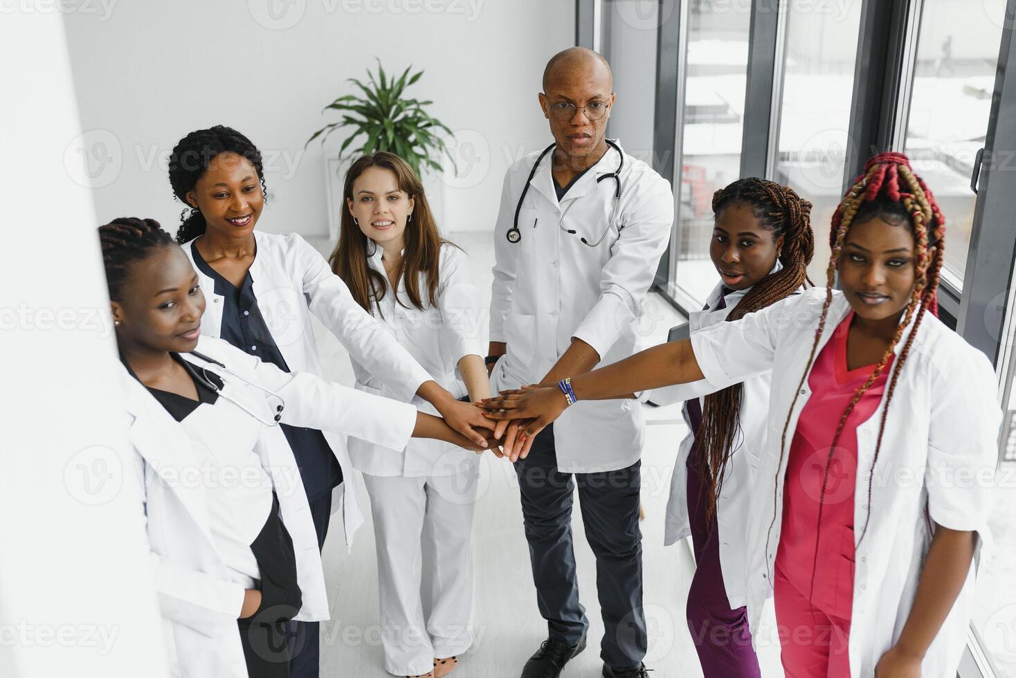Group of doctors putting hands together in clinic. Unity concept. photo