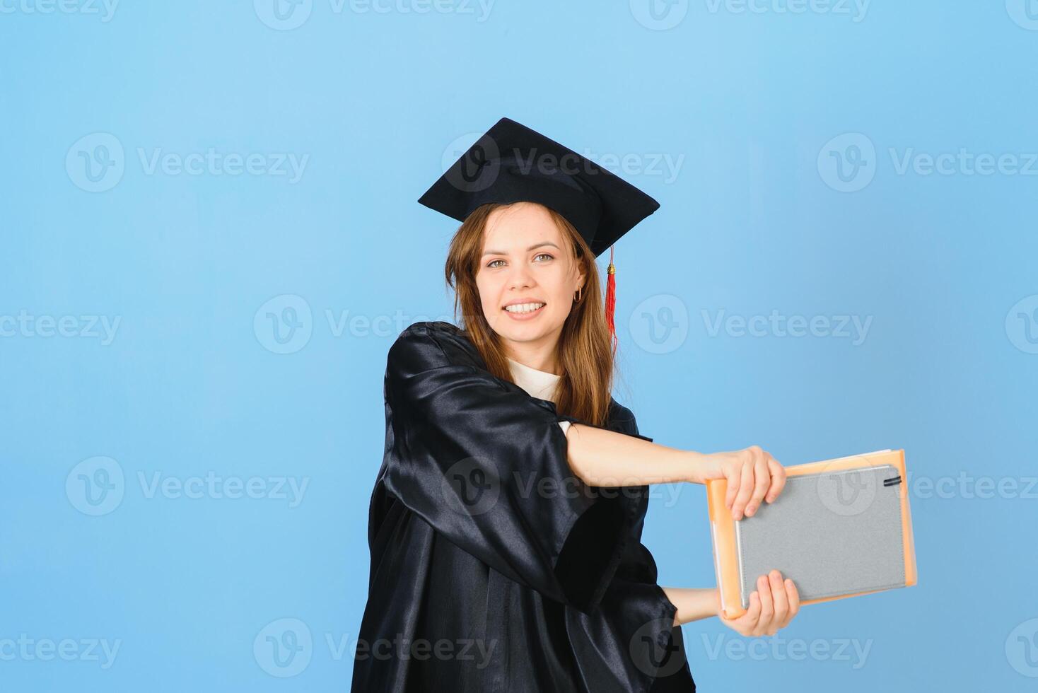 Beautiful woman wearing graduation cap and ceremony robe holding degree looking positive and happy standing and smiling with a confident smile. photo