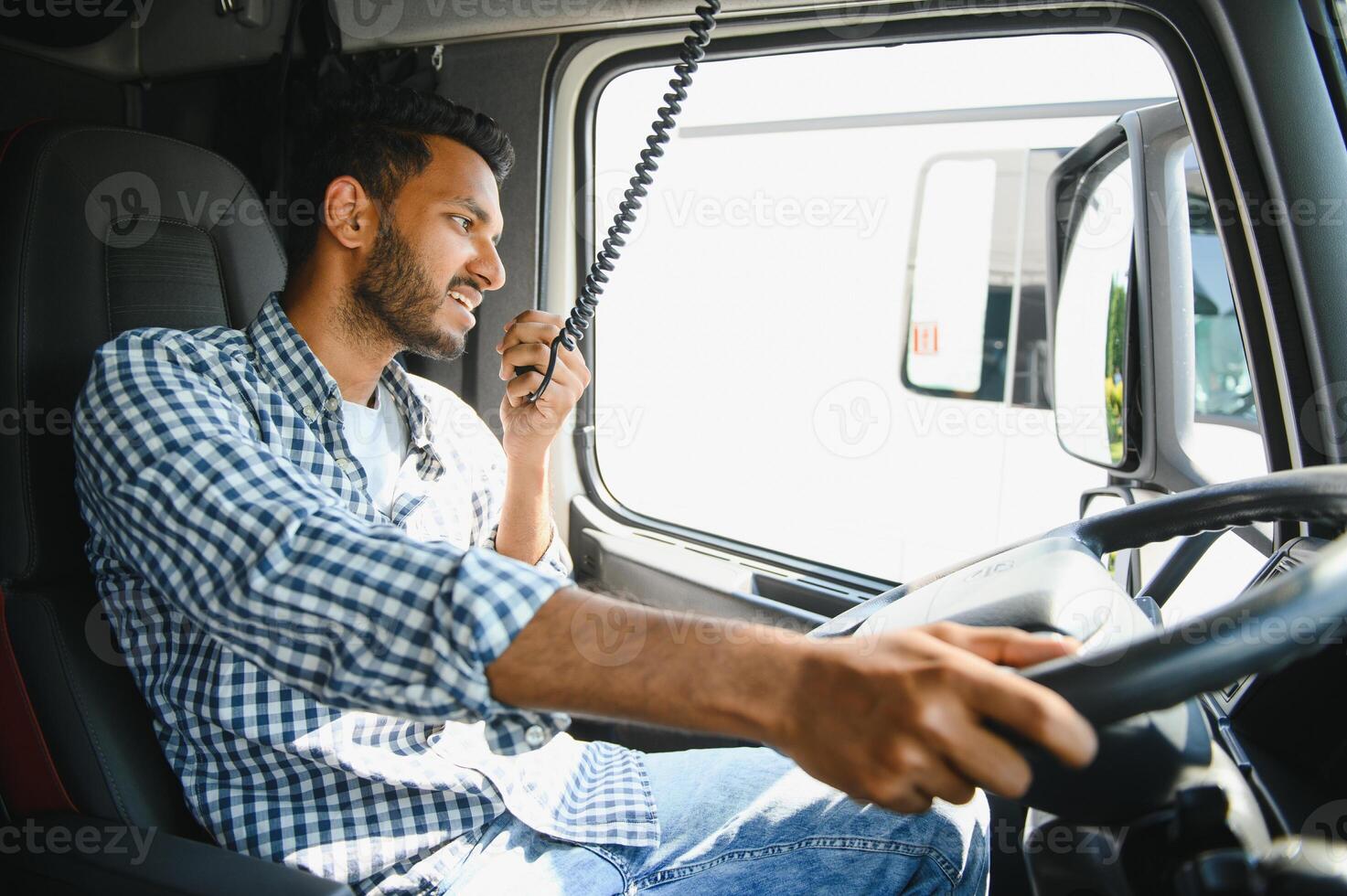 Using radio. Young truck driver is with his vehicle at daytime. photo