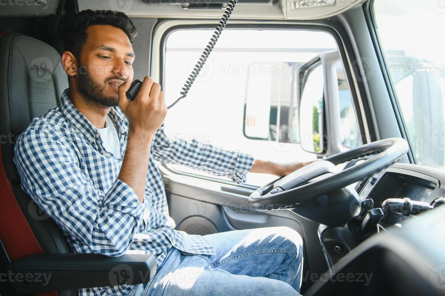 Using radio. Young truck driver is with his vehicle at daytime. photo