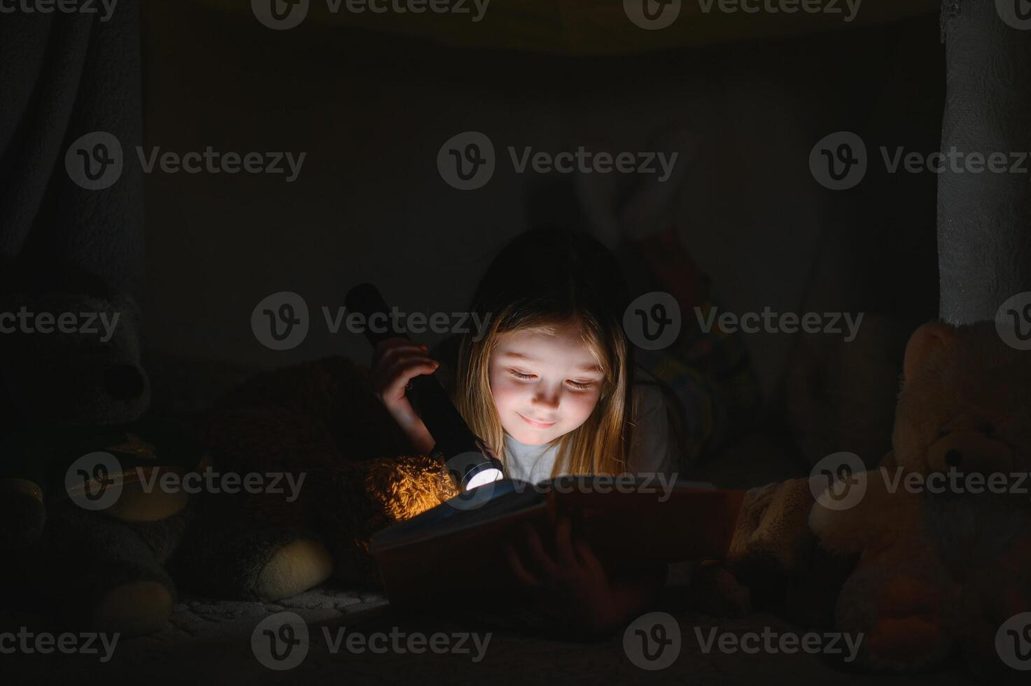 A pretty little girl reading a book on the floor under the lamp. Children and education. photo