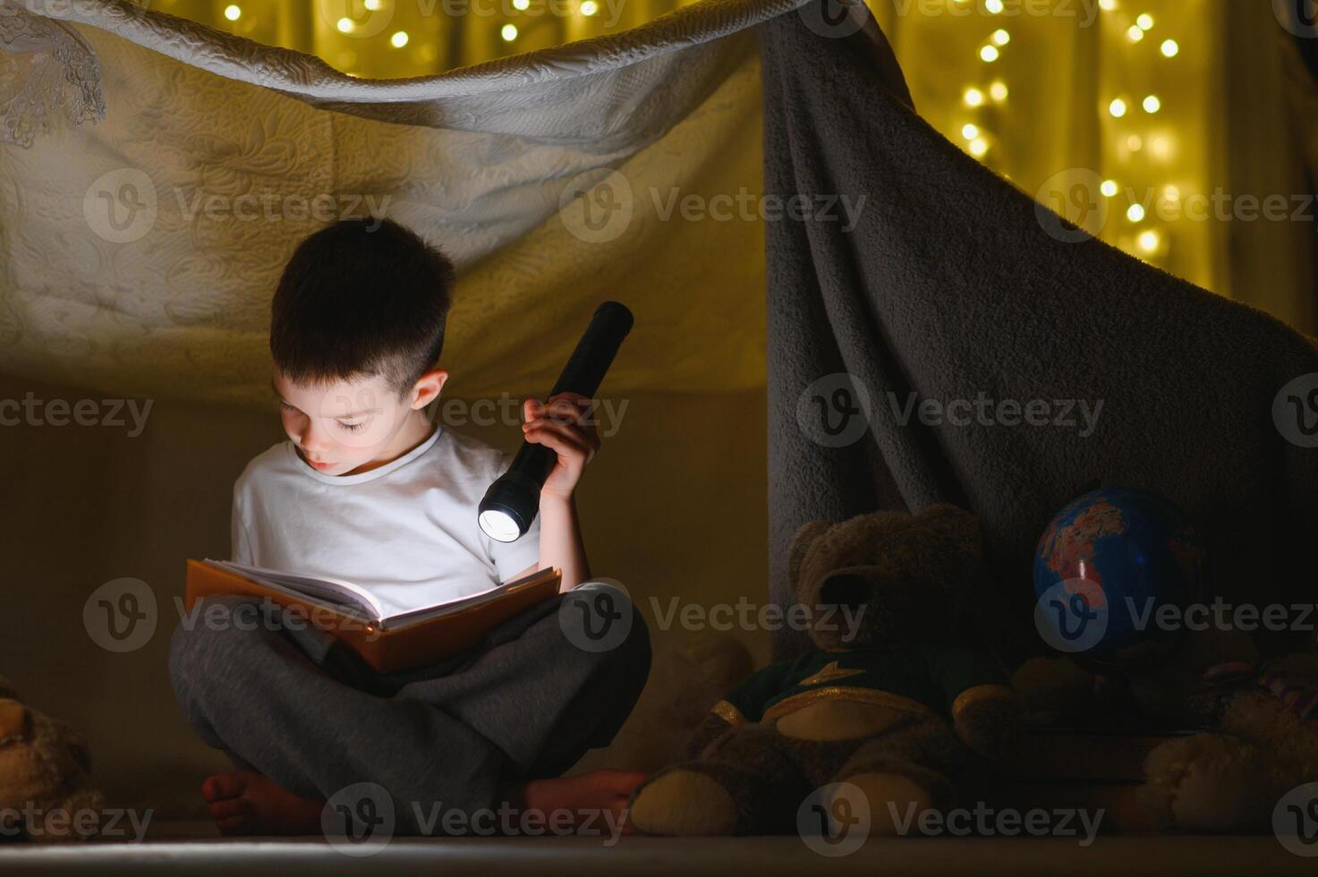 the child is reading a book with a flashlight photo