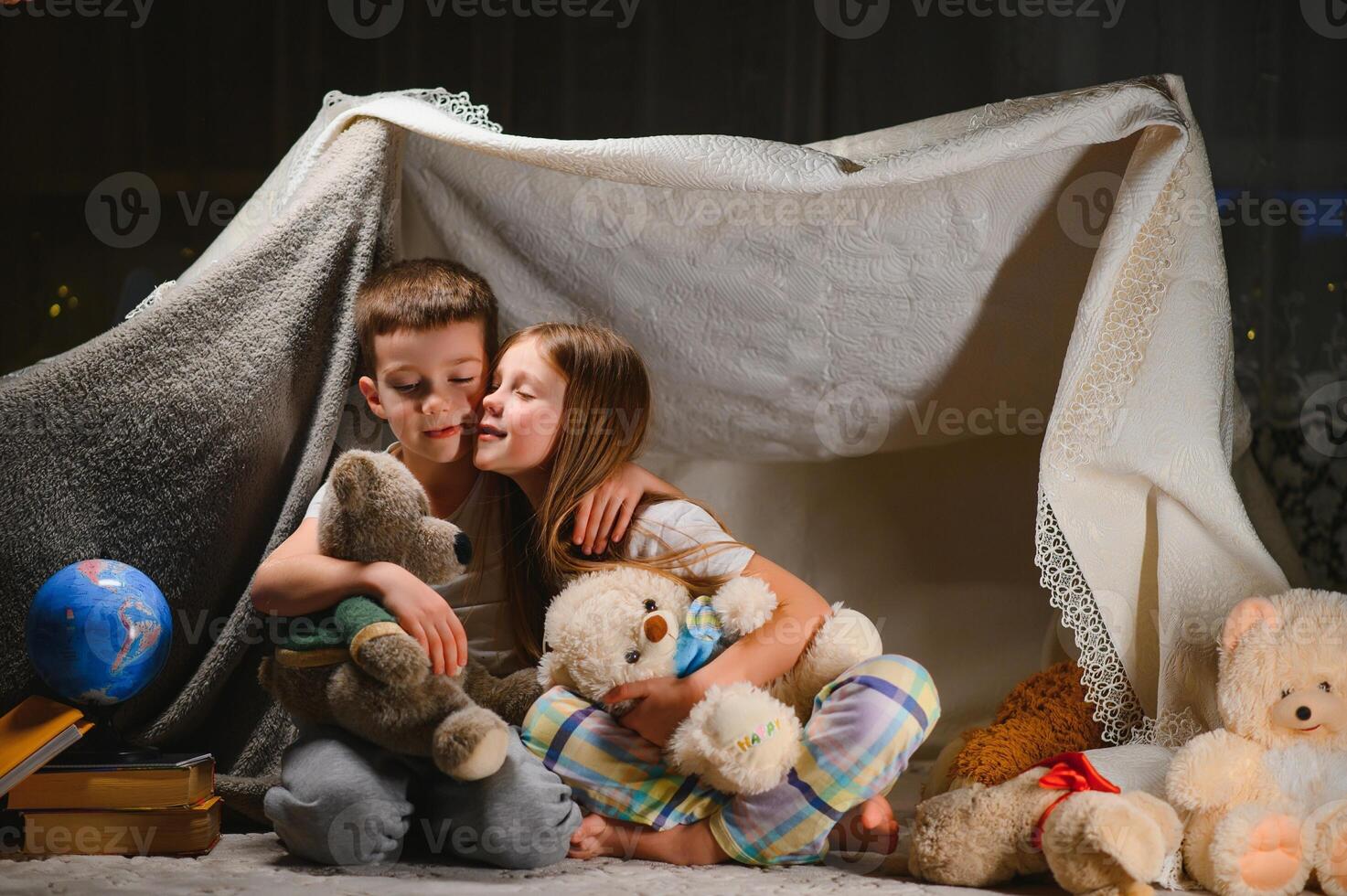 children boy and girl playing and frighten each other with flashlight in tent at night photo