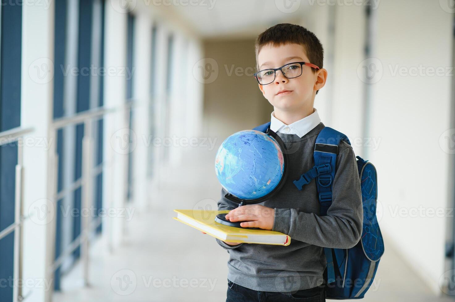 Schoolboy with schoolbag and books in the school. Education concept. Back to school. Schoolkid going to class. Stylish boy with backpack. Boy ready to study. photo