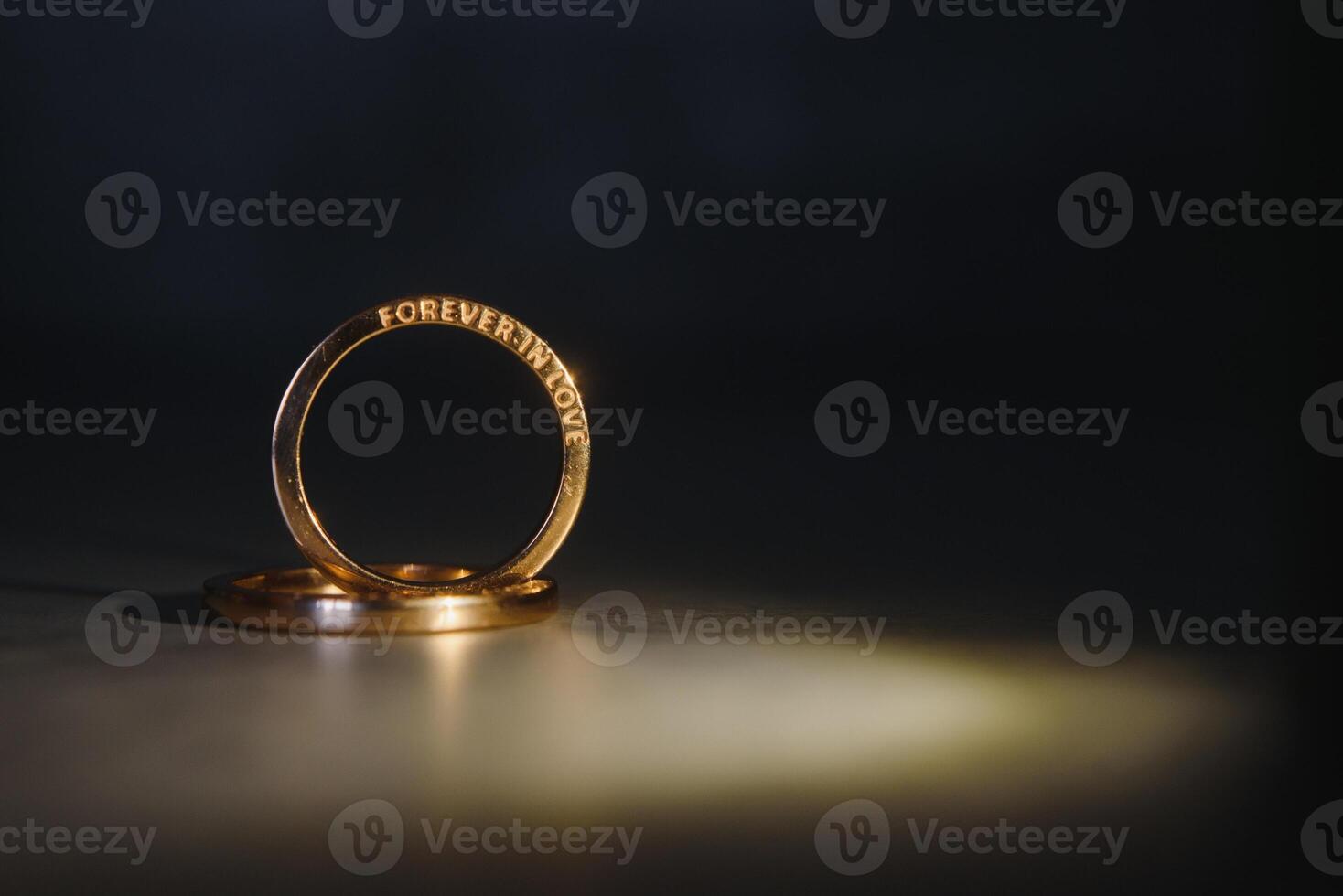 Elegant wedding rings for the bride and groom on a black background with highlights, macro, selective focus. photo