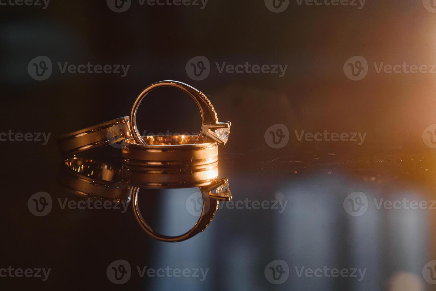Elegant wedding rings for the bride and groom on a black background with highlights, macro, selective focus. photo
