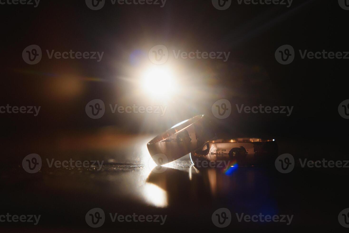 Elegant wedding rings for the bride and groom on a black background with highlights, macro, selective focus. photo