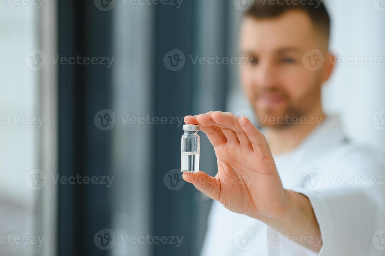 A doctor in blue gloves holding a bottle with vaccine. Close up shot. Medicine and healthcare concept. photo